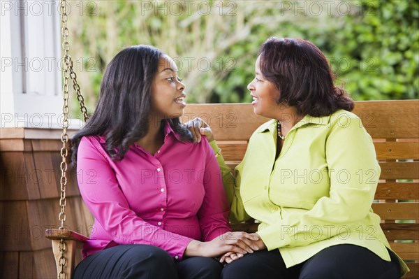 Mother and daughter talking on a porch swing