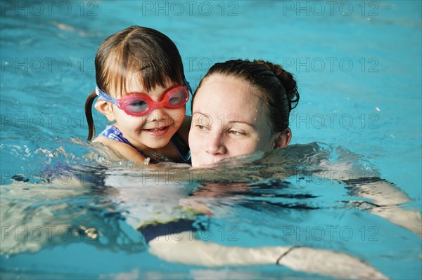 Mother and young daughter swimming