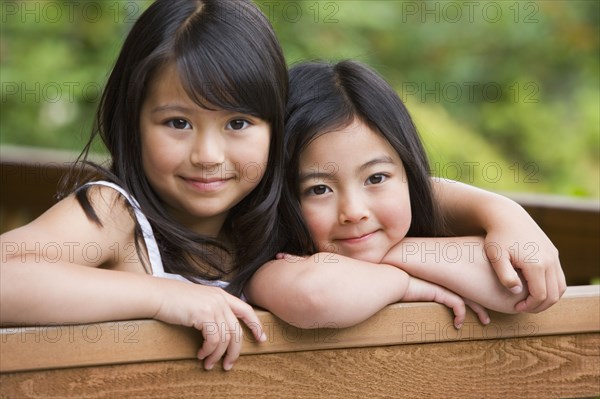 Young Asian sisters hugging and smiling outdoors