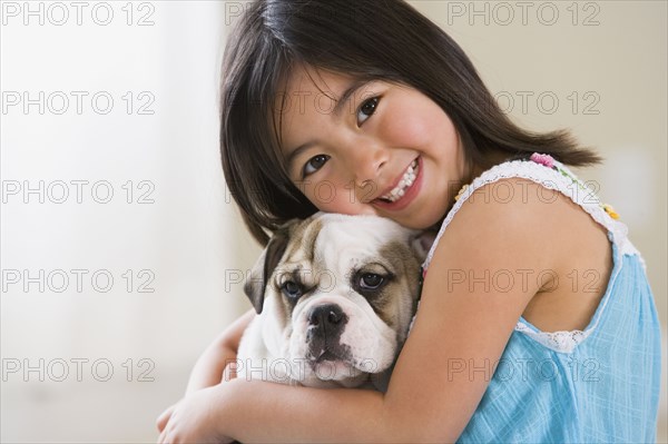 Young Asian girl smiling and hugging puppy