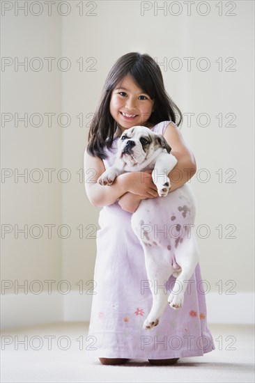 Young Asian girl smiling and holding puppy
