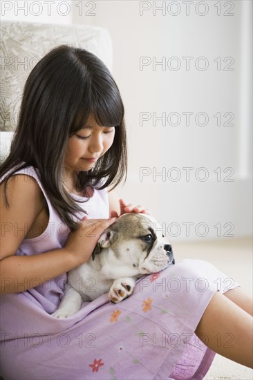 Young Asian girl petting puppy in lap