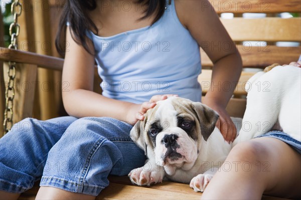 Girl petting puppy on porch swing