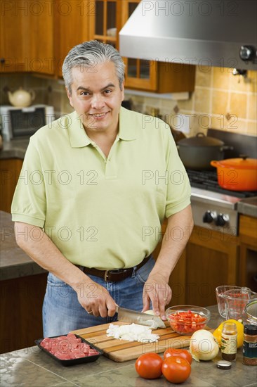 Hispanic man chopping vegetables in kitchen