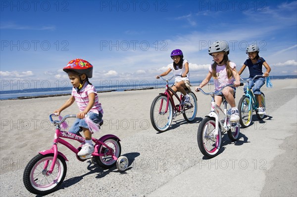 Young girls riding bicycles at beach