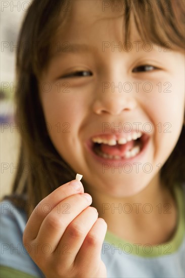 Asian girl smiling and holding tooth