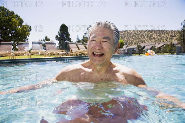 Senior Asian man laughing in swimming pool