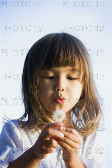 Asian girl blowing a dandelion