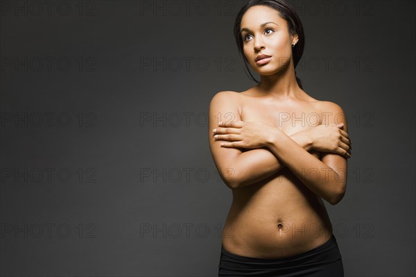 Semi-nude Hispanic woman with arms covering breasts