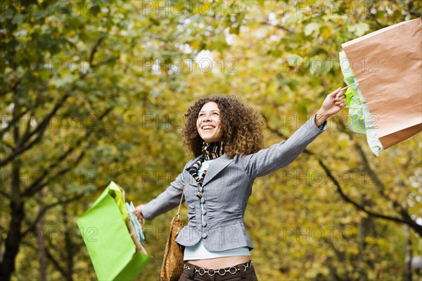 Hispanic woman swinging shopping bags in park