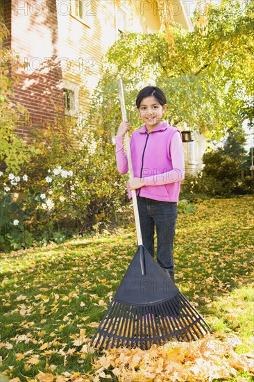 Hispanic girl raking leaves