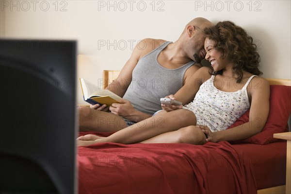 African couple cuddling in bed