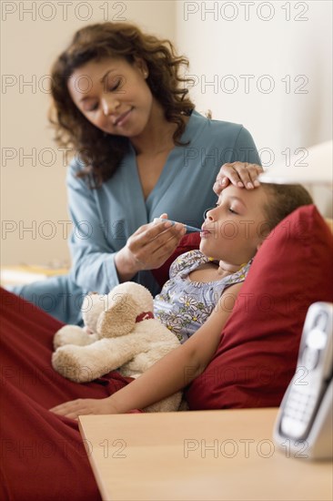 African mother taking daughter's temperature