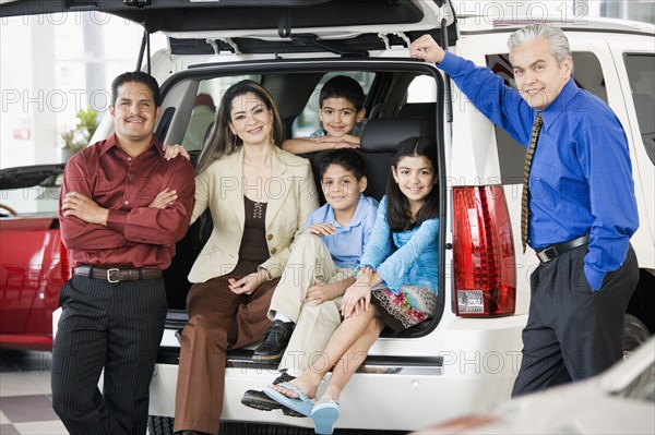 Hispanic family with salesman at car dealership