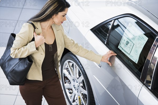 Hispanic woman looking at new car