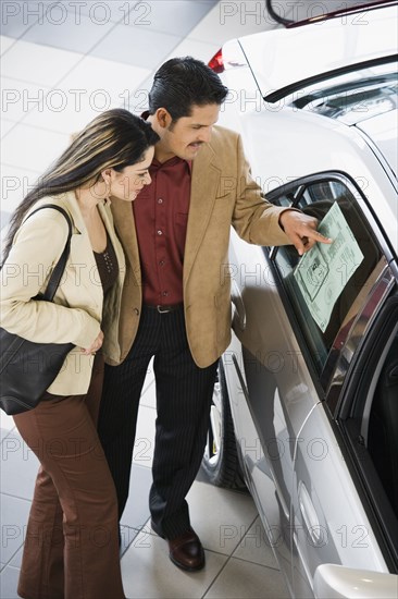 Hispanic couple looking at new car