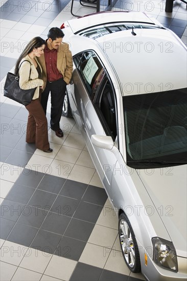 Hispanic couple looking at new car