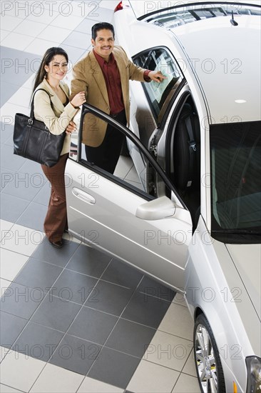 Hispanic couple looking at new car