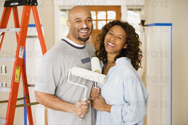 African couple being silly with paint rollers