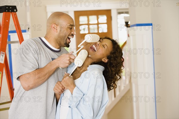 African couple being silly with paint rollers