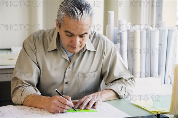Hispanic male architect writing at desk