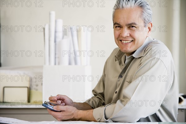 Hispanic male architect using electronic organizer