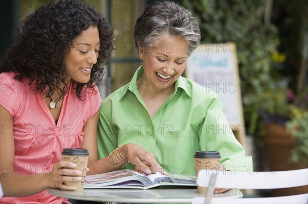 African American mother and adult daughter looking at photo album