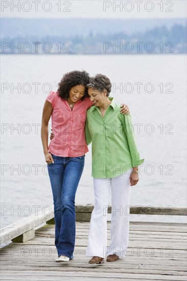 African American mother and adult daughter walking on pier