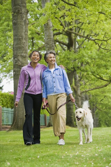 African American mother and adult daughter walking dog