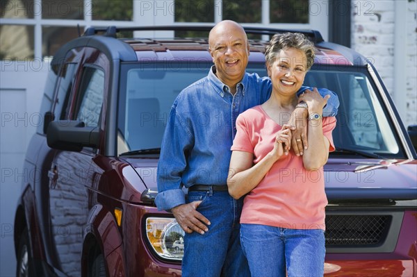 Senior African American couple leaning on car