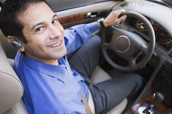 Hispanic businessman driving with earpiece