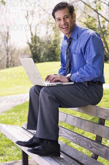 Hispanic businessman using laptop outdoors