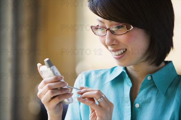 Asian woman smiling and using electronic organizer