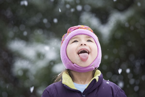 Asian girl sticking out tongue in snow