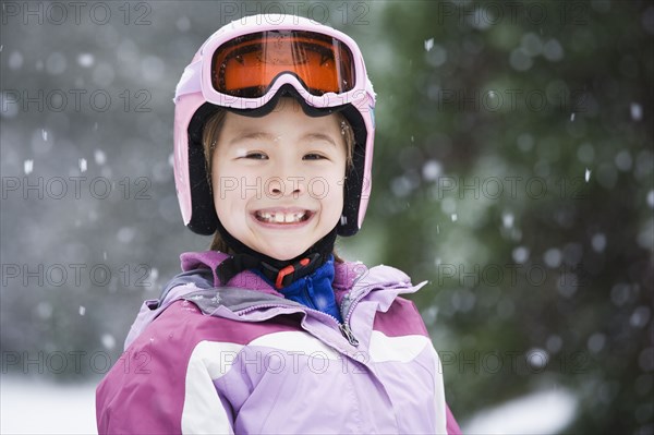 Asian girl wearing ski gear in snow