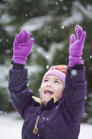 Asian girl with arms raised in snow