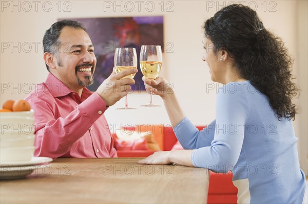 Hispanic couple toasting with wine