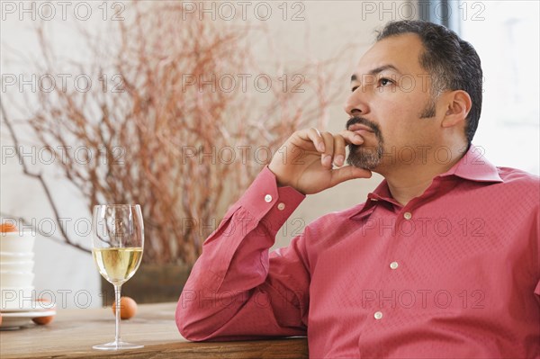 Hispanic man next to glass of wine