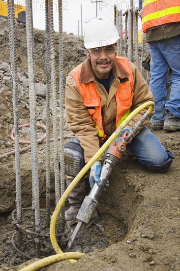 Hispanic construction worker holding equipment