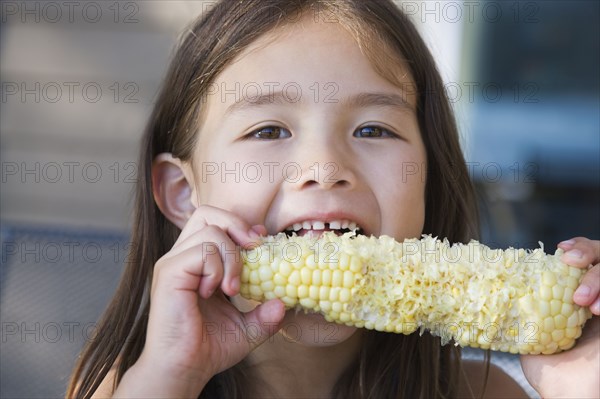 Asian girl eating corn on the cob