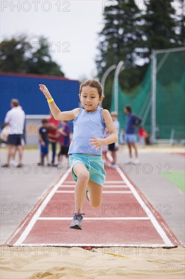 Asian girl performing long jump