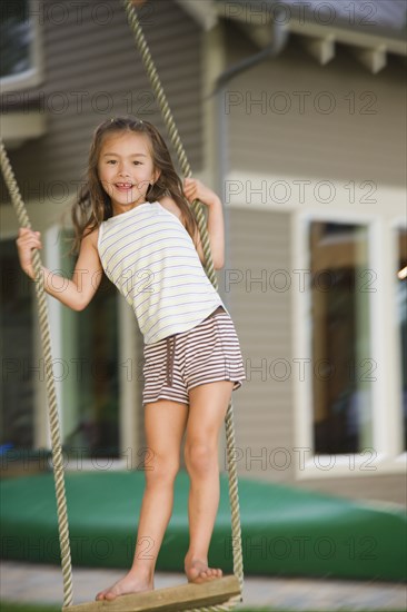 Asian girl swinging on rope swing