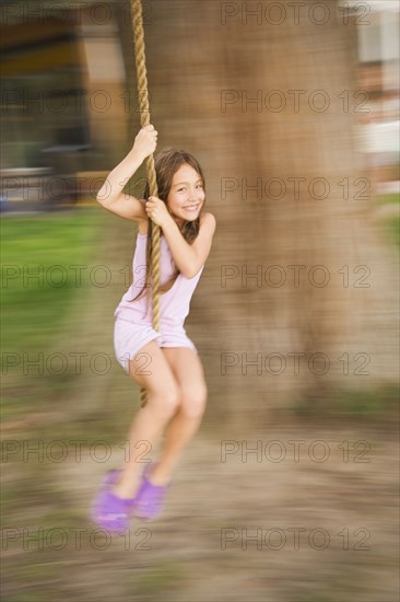 Asian girl swinging on rope swing