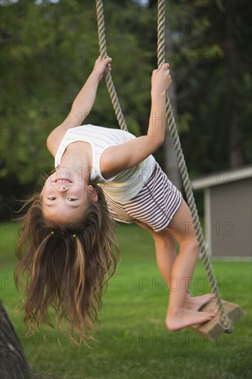 Asian girl swinging on rope swing