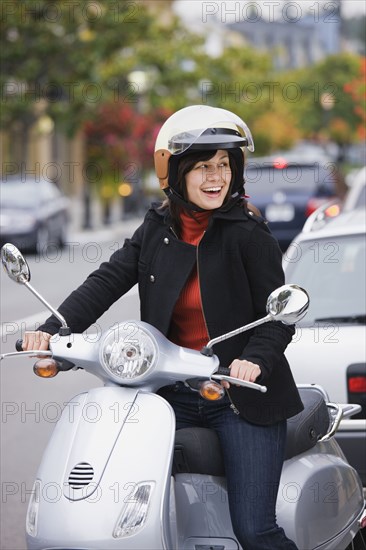 Mixed race woman in helmet driving scooter