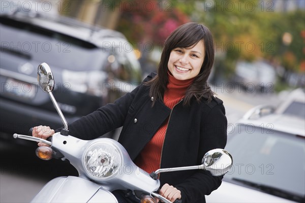 Mixed race woman driving scooter