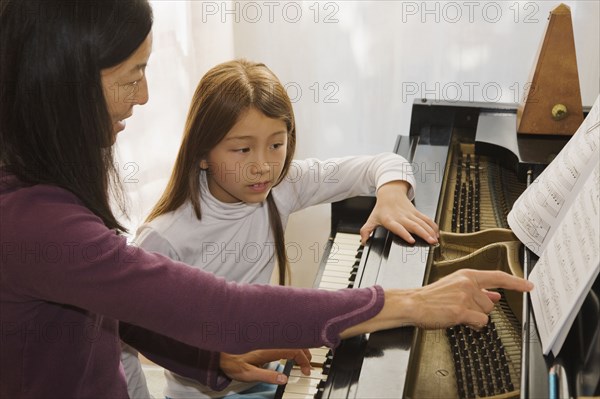 Woman teaching piano to young girl