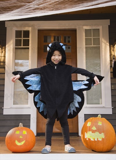 Young Chinese girl in butterfly costume with Halloween pumpkins