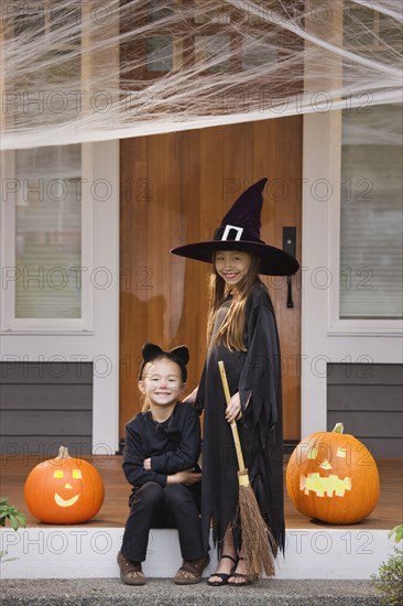 Mixed race young girls in cat and witch costumes