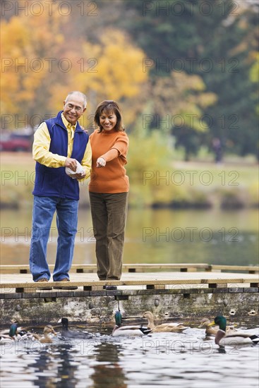 Hispanic couple feeding ducks in pond